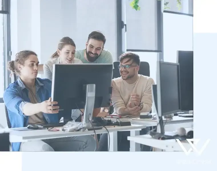 Menschengruppe sitzt am PC und schaut den Monitor an.