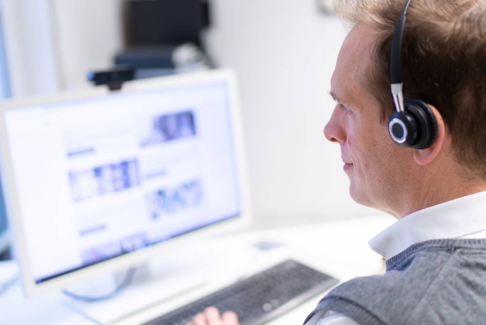 Ulrich Alt am PC mit einem Headset.
